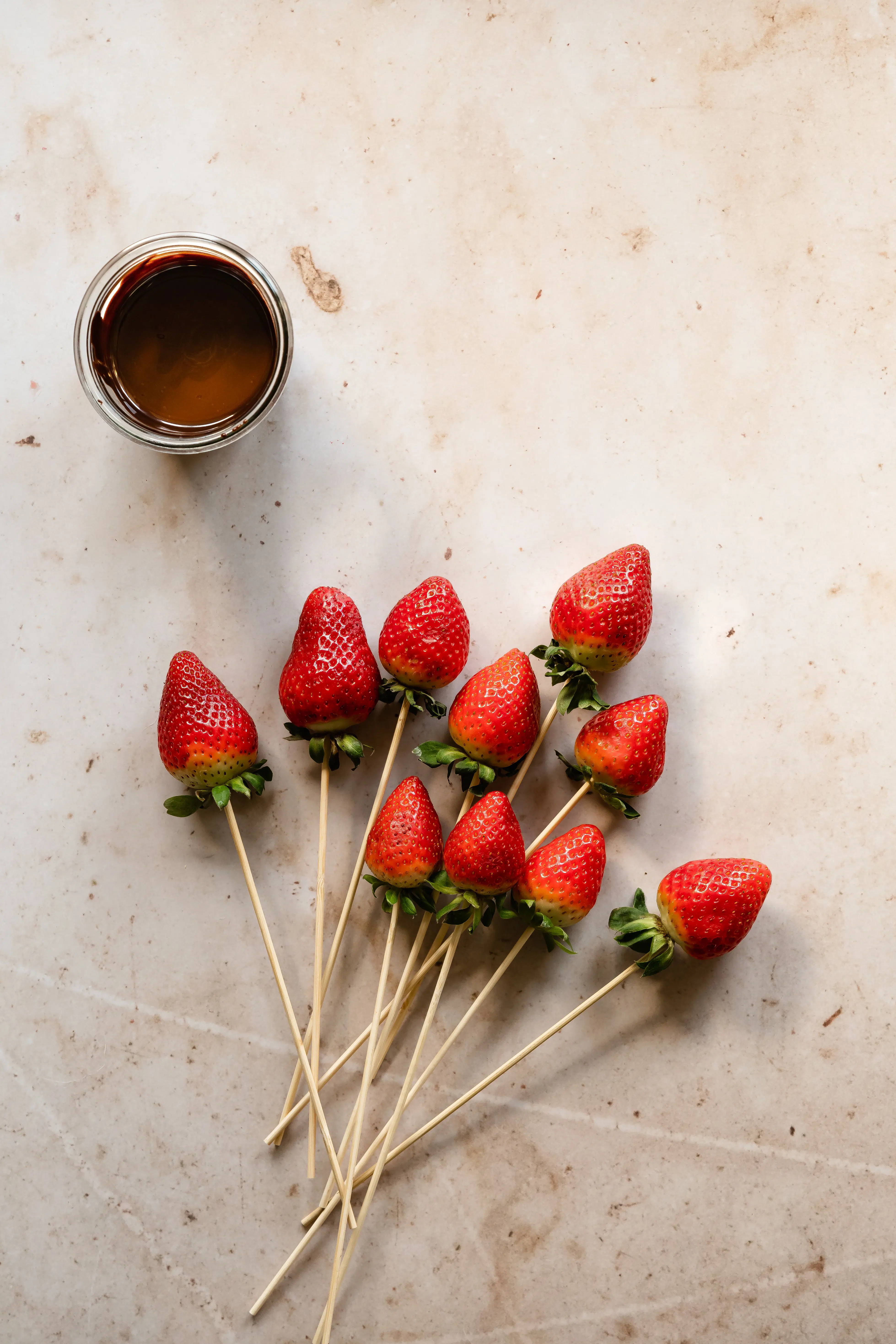 strawberries with bamboo skewers inserted into them before dipping in chocolate.