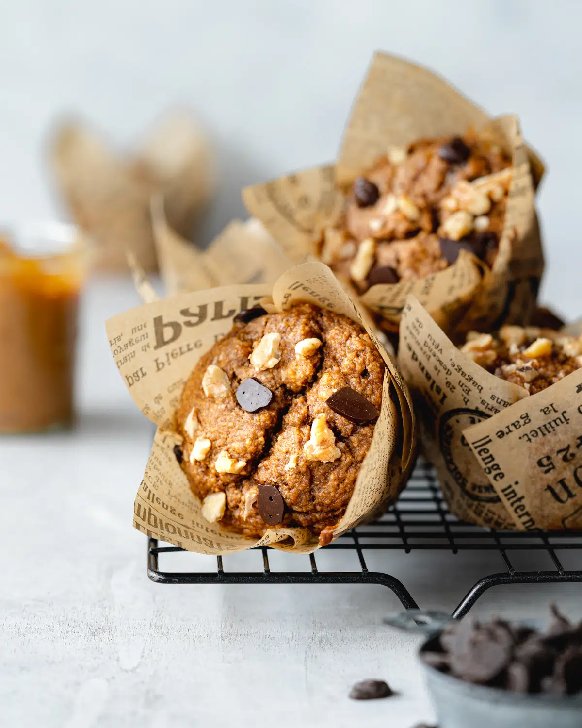 chocolate chip peanut butter banana muffins in tulip muffin cases on a cooling rack.