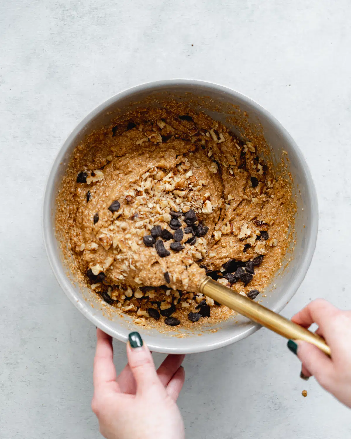 folding chocolate chips and walnuts into banana muffin batter.