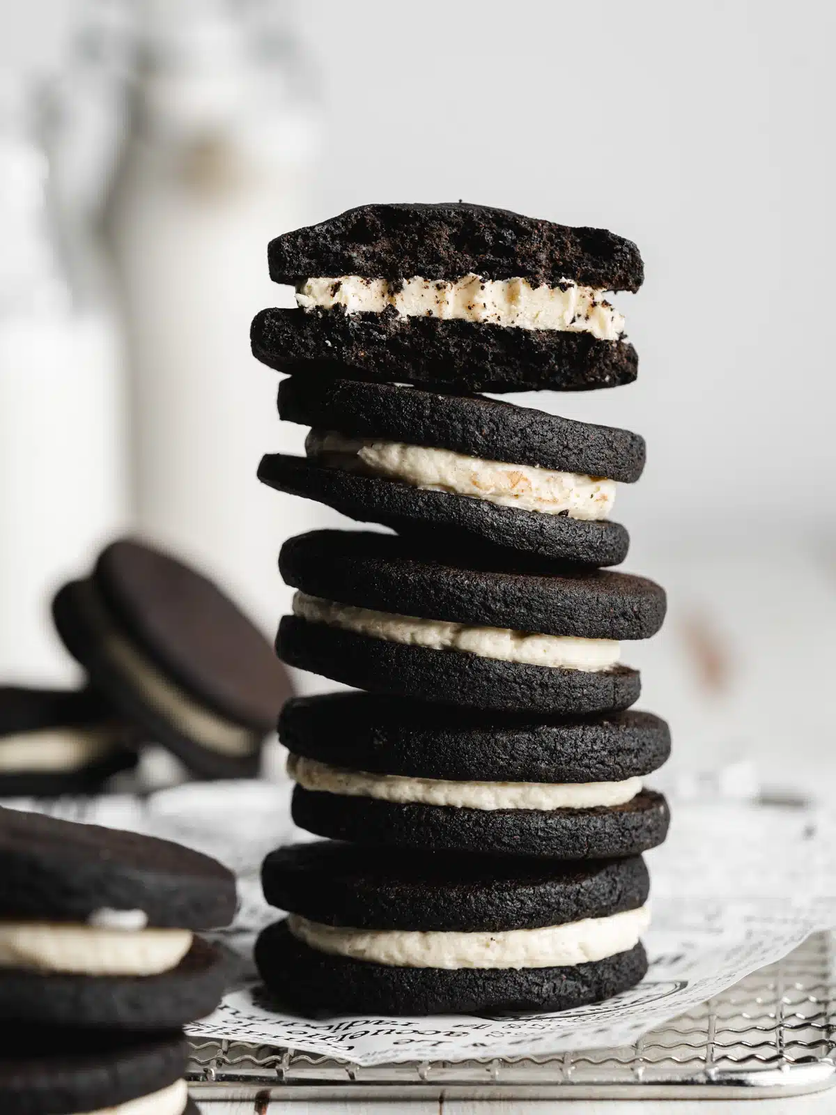 a stack of homemade oreo cookies with 2 glass milk bottles in the background.