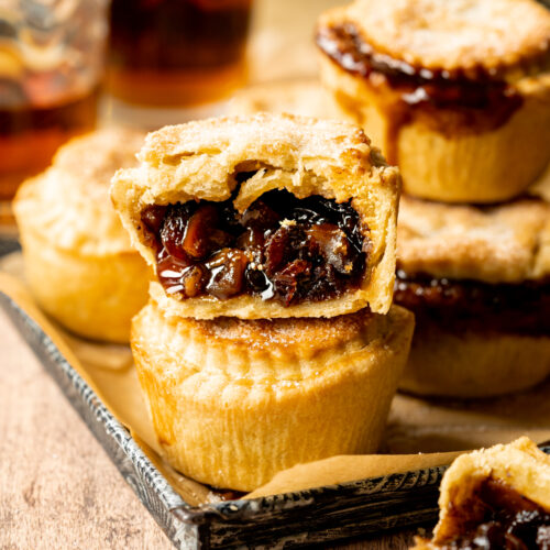 cross section of a vegan mince pie with more mince pies on a tray behind it.