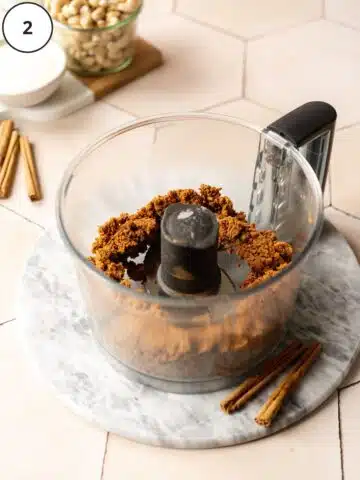 Biscoff cookie crust mixture in the base of a food processor after adding in the melted vegan butter.