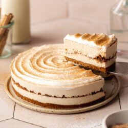 side-on hero shot of vegan no-bake cinnamon roll cheesecake with a slice being removed.