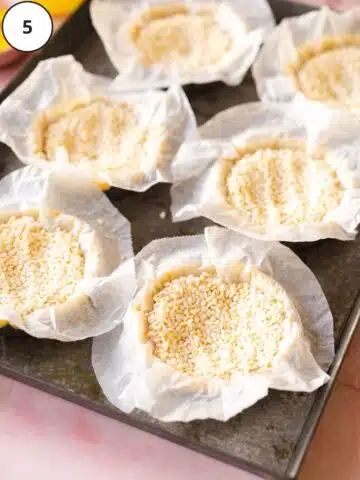 Tart shells are lined with parchment and filled with rice for blind baking.