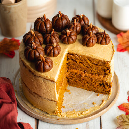 a pumpkin layer cake with biscoff filling topped with biscoff pumpkins on a ceramic plate.