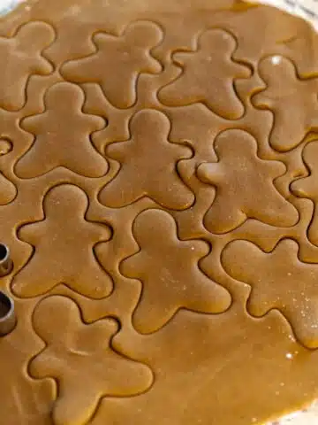 gingerbread cookie dough rolled out with gingerbread men cut outs.