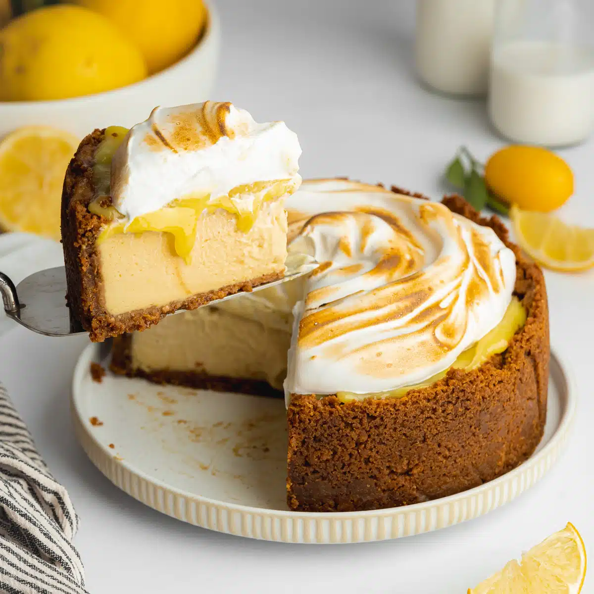 lemon cheesecake with meringue topping and a slice being lifted away on a cake slice.